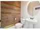 A rustic-style powder room with a wood accent wall and a round mirror above the pedestal sink at 1406 Stone Ridge Ct, Hampton, GA 30228