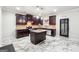 Kitchen featuring marble floors, dark cabinets, a granite island, and stainless steel appliances and a door to the outside at 1406 Stone Ridge Ct, Hampton, GA 30228