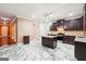 A modern kitchen featuring white marble floors, dark cabinets, a granite island, and stainless steel appliances at 1406 Stone Ridge Ct, Hampton, GA 30228
