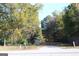 A view from the street showing the property's front yard, mature trees, and possible home location at 1372 Auburn Rd, Dacula, GA 30019