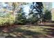 The lot is covered in dry leaves and grass with trees surrounding the buildable area at 1372 Auburn Rd, Dacula, GA 30019