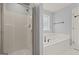 A renovated bathroom featuring a shower with glass door, a large tub, and gray walls at 85 Bloomfield Way, Sharpsburg, GA 30277