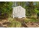 Exterior view of a neutral-colored storage shed in a wooded setting at 85 Bloomfield Way, Sharpsburg, GA 30277