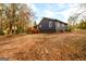 Exterior view of a dark gray house with a wooden deck and treehouse in the wooded backyard at 79 Turner Dr, Mcdonough, GA 30252