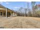 Side view of home's backyard with sprawling lawn and a covered patio to the side; view of forest in the background at 426 Ayers Rd, Bowdon, GA 30108