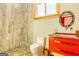 Stylish bathroom showcases a vanity with a red cabinet, a circular mirror, and tiled shower at 242 Kirkley Rd, Tyrone, GA 30290
