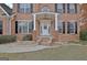 Inviting entryway with white front door, pillars, and brick steps, framed by manicured shrubs and dark shutters at 355 Woodbyne Dr, Fayetteville, GA 30214