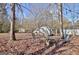 Leaf-covered backyard featuring a brick fire pit with chairs, storage shed, and mature trees at 435 Crabapple Rd, Fayetteville, GA 30215