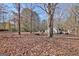 Leaf-covered backyard with a stone fire pit, mature trees, playset, and storage building at 435 Crabapple Rd, Fayetteville, GA 30215