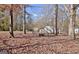 Leaf-covered backyard featuring a cozy fire pit area, storage shed, and mature trees for privacy at 435 Crabapple Rd, Fayetteville, GA 30215