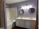 Bathroom featuring a double vanity, round mirrors, and a tub/shower combination at 7472 Woods Ct, Lithonia, GA 30058