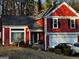 Front exterior of red two-story home with a two-car garage and mature landscaping at 7472 Woods Ct, Lithonia, GA 30058