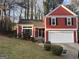 Charming red two-story home with black shutters, white garage door, and well-manicured front lawn at 7472 Woods Ct, Lithonia, GA 30058