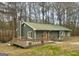 Cozy single-story home features a wooden deck, a metal roof, and lush green surroundings at 2020 Moore Rd, Moreland, GA 30259