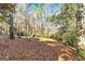 View of wooded backyard with leafy ground and a swing set in the distance at 232 Terrane Rdg, Peachtree City, GA 30269