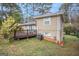 View of back exterior featuring a deck, brick foundation, vinyl siding, landscaping, and trees surrounding the property at 3435 Misty Valley Rd, Decatur, GA 30032