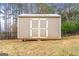 Tan storage shed with white double doors at 209 Enfield Ln, Mcdonough, GA 30252