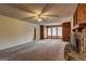 Carpeted living room features a stone fireplace, ceiling fan, and wood-paneled walls with lots of windows at 3954 Swathmore Ln, Duluth, GA 30096