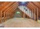 Unfinished attic space featuring exposed wood beams, a small window, and plywood flooring, ready for customization at 65 Riverside Way, Sharpsburg, GA 30277