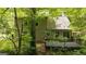 Backyard view with an outdoor deck, surrounded by mature trees and lush greenery, offering privacy and a natural setting at 65 Riverside Way, Sharpsburg, GA 30277