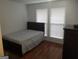 Bedroom with laminate wood flooring, a queen-size bed, and two windows with blinds at 3248 Brisbane Way, Lithonia, GA 30038