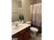 Bathroom with wood vanity, neutral shower curtain, and white toilet at 6022 Centennial Run, Atlanta, GA 30349