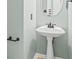 Small powder room with pedestal sink and round mirror at 180 Rock Hill Dr, Fayetteville, GA 30215