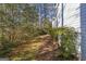 Side yard with mature plantings in the foreground, and natural wooded area in the background at 730 N Bethany Rd, Mcdonough, GA 30252