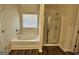 This bathroom features a tub, shower, wood-look floors, and a large window at 2791 Riverchess Ct # 147, Atlanta, GA 30331