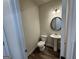 A powder room features a pedestal sink, round mirror, and wood-look floors at 2791 Riverchess Ct # 147, Atlanta, GA 30331