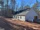 Rear view of a new home showcasing gray siding, a two-car garage, and a wooded setting at 5525 Belle Meade Dr, Villa Rica, GA 30180