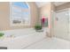 Bright bathroom features a large soaking tub under a sunny arched window and glass shower at 600 English Ct, Mcdonough, GA 30252