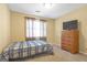 Cozy bedroom with a plaid bedspread, a window with curtains, and a wooden dresser at 2618 Windage Sw Dr, Marietta, GA 30008