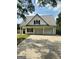 White house with gray metal roof, three-car garage, and a spacious driveway at 470 Harris Rockmore Loop, Covington, GA 30014