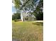 White house with gray metal roof, three-car garage, and a long driveway at 470 Harris Rockmore Loop, Covington, GA 30014