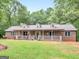 Brick ranch house with a wraparound porch and landscaped yard at 930 Singley Dr, Locust Grove, GA 30248