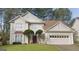 Two-story house with a tan exterior, red door, and a two-car garage at 635 Watson Bay, Stone Mountain, GA 30087