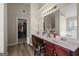 Well-lit bathroom with a dual sink vanity, dark wood cabinets, and a door leading to a walk-in closet at 319 Allegrini Dr, Atlanta, GA 30349