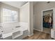 Bright bathroom features a soaking tub with a window, tiled backsplash, and a closet at 319 Allegrini Dr, Atlanta, GA 30349