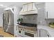 Modern kitchen with white cabinets, gold range hood, and stainless steel appliances at 1153 Dawn View Nw Ln, Atlanta, GA 30327