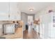 White kitchen cabinets, tile backsplash, and wood-look floors. View to dining area at 718 Grove Pointe Cir, Locust Grove, GA 30248