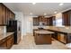 Well-equipped kitchen with stainless steel appliances, granite countertops, and abundant dark wood cabinetry for storage at 5345 Bucknell Trce, Cumming, GA 30028