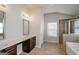 Bathroom featuring double vanity, framed mirrors, walk-in shower, tub, and tiled floors at 5345 Bucknell Trce, Cumming, GA 30028