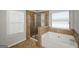 Bathroom featuring tiled walls, a glass enclosed shower, soaking tub, and window at 5345 Bucknell Trce, Cumming, GA 30028