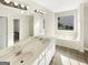 Well-lit bathroom with dual sinks, vanity, and a garden tub next to a window at 1535 Valley Club Dr, Lawrenceville, GA 30044