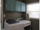 Bright laundry room with teal cabinets and window at 155 Carriage Gate Dr, Sharpsburg, GA 30277