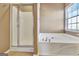 A bathroom with a walk in shower, and separate tub under a window at 704 Pine Grove Cir, Peachtree City, GA 30269