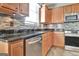 Well-lit kitchen with granite countertops, stainless steel appliances, tile backsplash, and wood cabinetry at 704 Pine Grove Cir, Peachtree City, GA 30269