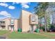 Tan two-story townhouse with green lawn and mature trees at 6036 Regent Mnr, Lithonia, GA 30058