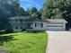 Charming split-level home featuring a two-car garage, well-manicured lawn, and a tree-lined backdrop at 6667 Ridge Moore Dr, Peachtree Corners, GA 30360